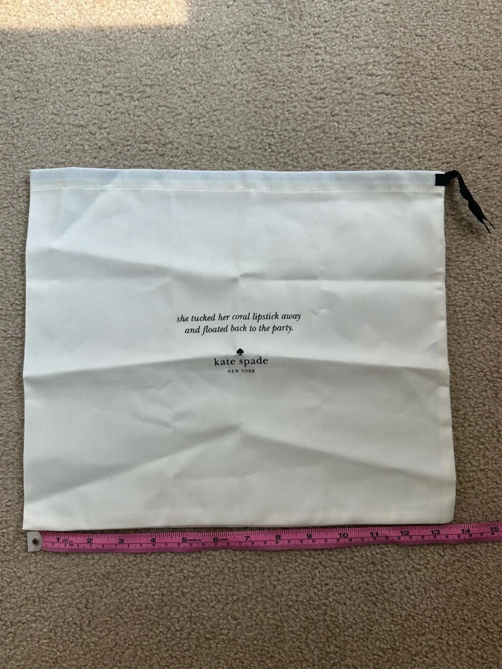 Kate Spade New York cream dust bag with black text and logo